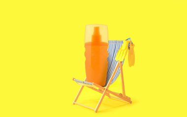 Sarı arka planda plaj sandalyesi ve bir şişe güneş kremi.