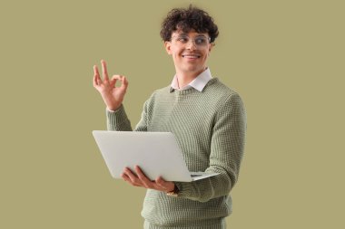 Laptoplu genç adam yeşil arka planda iyi görünüyor.