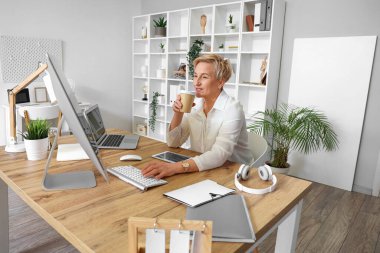 Ofiste çalışan olgun bir kadın programcı ve bir fincan kahve.