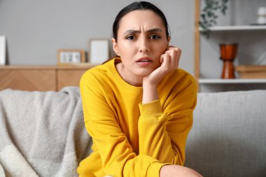 Evdeki kanepede video sohbeti yapan genç bir kadın.