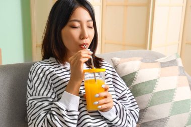 Güzel Asyalı kadın evde meyve suyu içiyor, yakın plan.