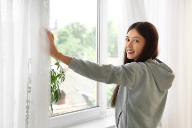 Evinin penceresinin yanındaki şık kapüşonlu güzel Asyalı kadın.