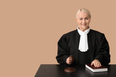 Kahverengi arka planda tokmak ve kitap bulunan olgun kadın yargıç.