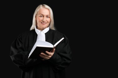 Siyah arka plan kitabı olan olgun bir kadın yargıç.