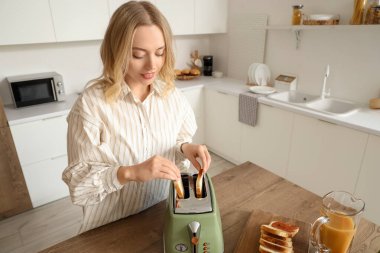 Genç, güzel, mutlu bir kadın mutfakta lezzetli tostlar yapıyor.