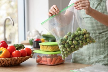 Mutfakta donmak için elinde Brüksel lahanası olan plastik poşet tutan kadın.