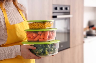 Mutfakta dondurmak için plastik kapları sebzelerle tutan kadın, yakın plan.