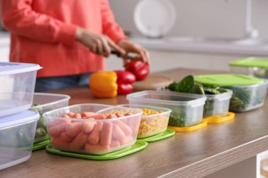 Sebzeli plastik kaplar ahşap masada donmak için kadınlar da arka planda.