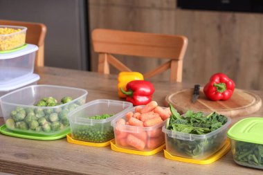 Mutfaktaki ahşap masada dondurmak için sebzeli plastik kaplar.