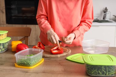 Mutfaktaki ahşap masada donmak için biber kesen kadın.