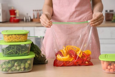 Ahşap masada donmak için elinde dolma biberle plastik poşet tutan kadın.