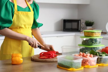 Mutfaktaki ahşap masada donmak için biber kesen kadın.