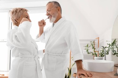 Banyoda dişlerini fırçalayan olgun bir çift.