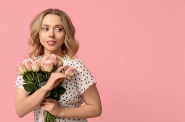 Pembe arka planda gül buketi olan genç bir kadın.