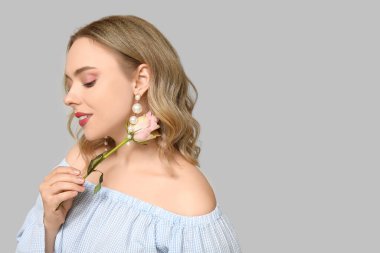 Gri arka planda güzel gülleri olan genç bir kadın.