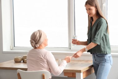 Kemoterapiden sonra olgun bir kadın mutfaktaki kızından hap alıyor. Mide kanseri kavramı