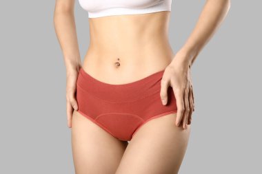 Gri arka planda külotlu genç bir kadın.