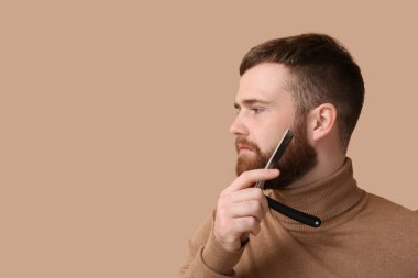 Genç sakallı adam, açık jilet renginde.