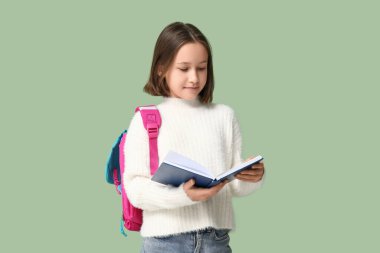 Little schoolgirl reading book on green background clipart