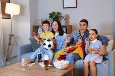 İspanyol bayraklı mutlu bir aile akşamları evdeki kanepede futbol maçı izliyor.