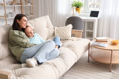 Mutlu anne ve küçük kızı evdeki kanepede televizyon izliyorlar.