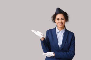 Gri arka planda bir şey gösteren güzel Afro-Amerikan hostes.