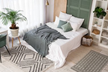 Yatak odasının içinde raf ünitesi, bitkiler ve yatak var.