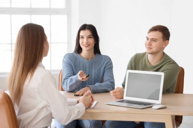 Genç çift emlakçının ofisinde yeni bir ev almayı tartışıyor.