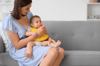 Anne ve küçük bebeği evde yemek yiyorlar.