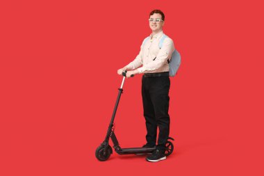 Kırmızı arka planda modern elektrikli scooterı olan mutlu erkek öğrenci.