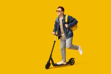 Sarı arka planda modern elektrikli scooter kullanan erkek öğrenci.