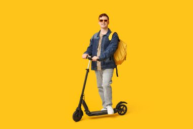 Sarı arka planda modern elektrikli scooter kullanan erkek öğrenci.