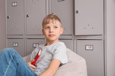 Okulda dolabının yanında kitabı olan şirin bir çocuk.