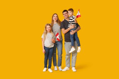 Sarı arka planda Kanada bayrakları olan mutlu bir aile