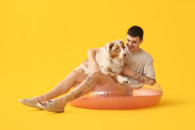 Sarı arka planda yüzen Avustralya çoban köpeği olan genç adam.