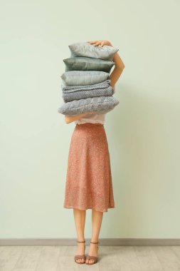 Yastık yığını ve katlanmış ekoseli kadın ışık duvarının yanında