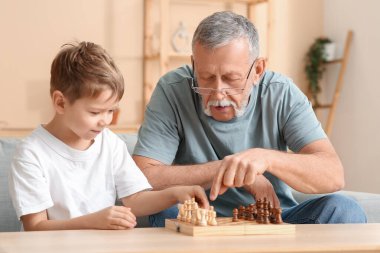 Büyükbaba ve küçük tatlı torunu evde satranç oynuyorlar.