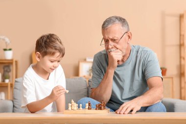 Büyükbaba ve küçük tatlı torunu evde satranç oynuyorlar.