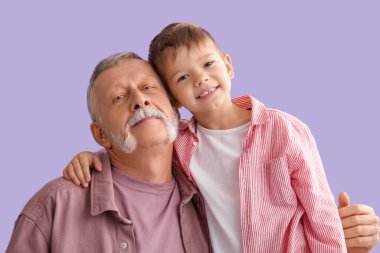 Büyükbaba, küçük tatlı torunu mor arka planda sarılıyor.