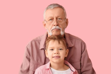 Pembe arka planda küçük, mutlu torunu olan büyükbaba.