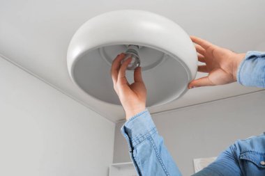 Evdeki lambanın ampulünü değiştiren adam.