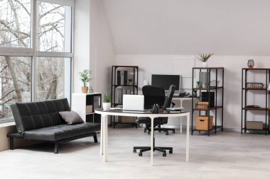 Tabloları ve raf üniteleri olan modern ofis.