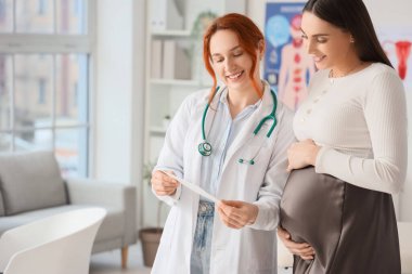 Kadın doktor klinikteki hamile kadına ultrason görüntüsü gösteriyor.
