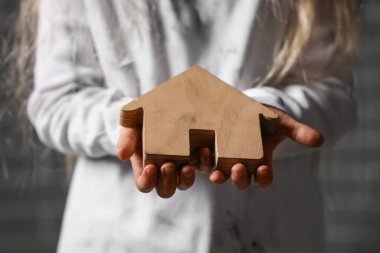 Evsiz küçük kız ev figürü, yakın plan.