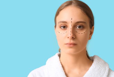 Yüzünde mavi arka planda izler olan genç bir kadın. Blepharoplasty konsepti