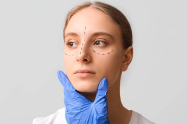 Plastik cerrah gri arka planda kadının yüzünü inceliyor. Blepharoplasty konsepti