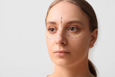 Yüzünde gri arkaplan izleri olan genç bir kadın. Blepharoplasty konsepti