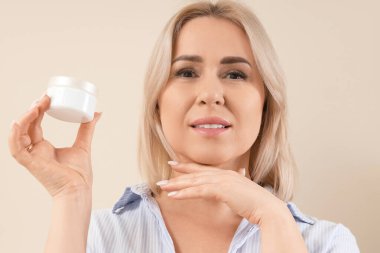 Güzel, olgun, mutlu, bej arka planda krema dolu bir kadın.