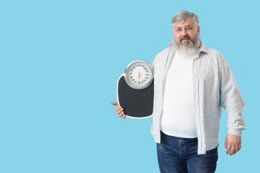 Mavi arka planda pulları olan şişman, olgun, mutlu bir adam. Kilo verme konsepti