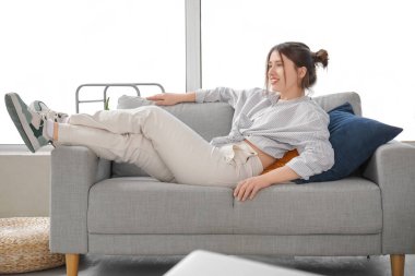 Evdeki kanepede dinlenen mutlu genç bayan.